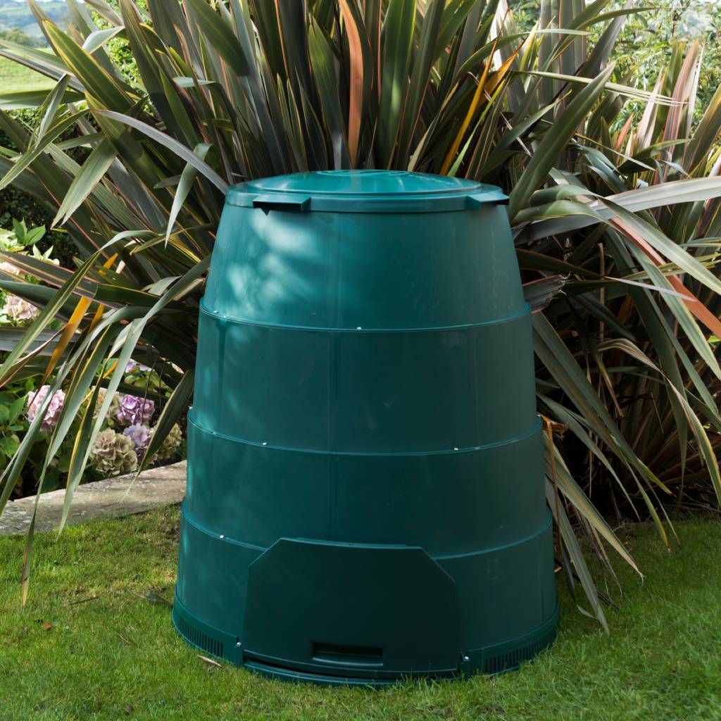 Green Johanna garden composter with winter jacket standing on grass in front of phormium