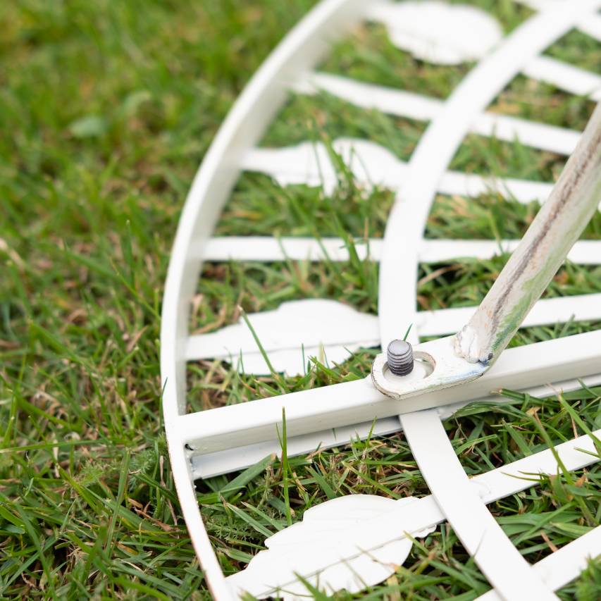 Underside view of cream Blaisdon bistro table on lawn, highlighting the bolt fixing.