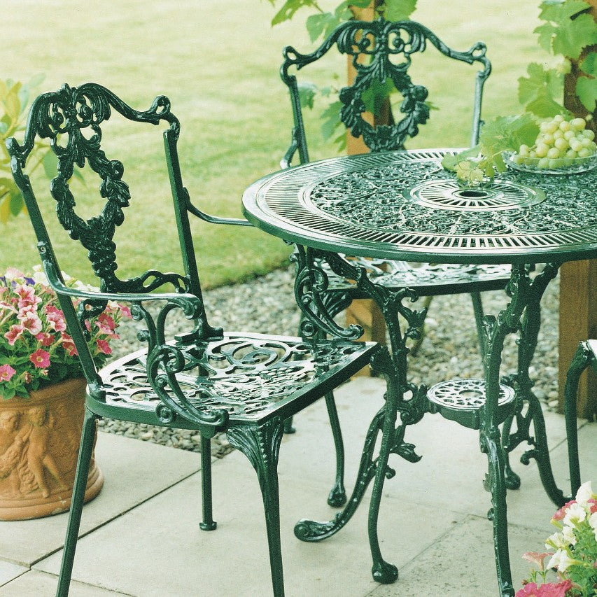 Two Jardine Leisure Grape carver chairs with Coalbrookdale round table in green finish on patio under pergola with grape vine