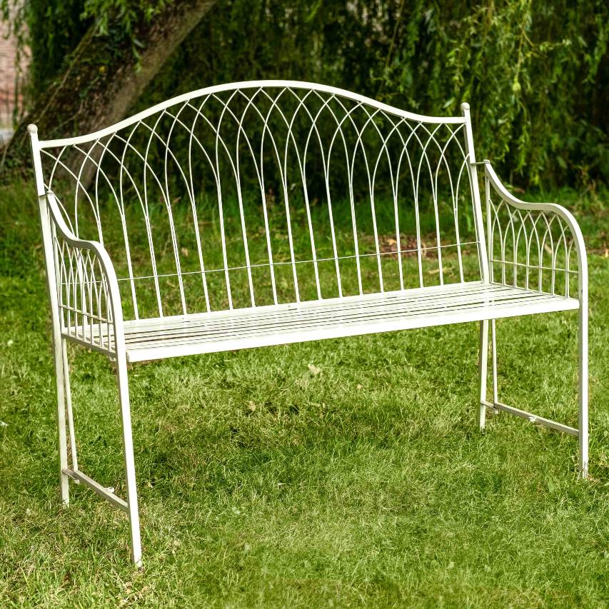 Cream Hampton bench on grass with trees in the background.