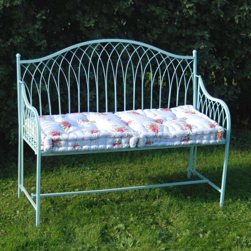 Pale blue Hampton bench with floral cushions on a grassy area.