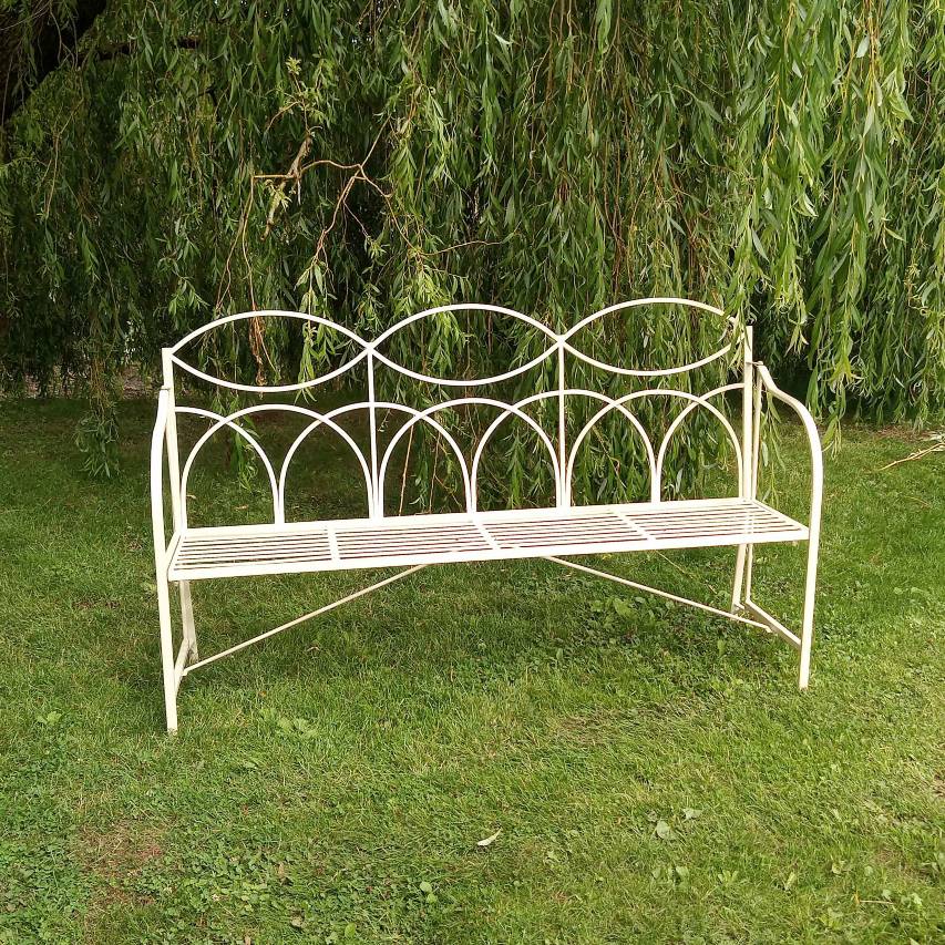Cream 3-seater reeded bench placed on grass beneath overhanging willow branches.