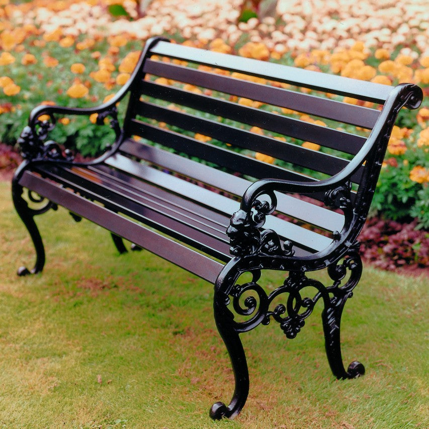 Jardine Leisure Sandringham bench in satin black with iroko hardwood slats placed on lawn next to flowerbed