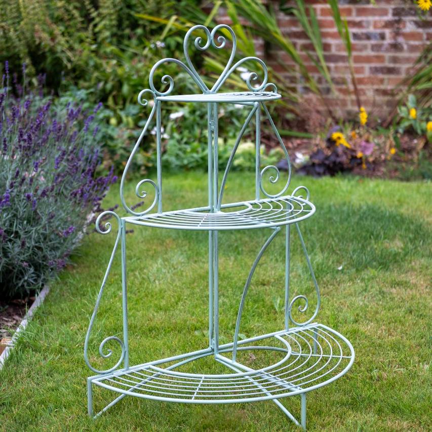 3-tier heart etager in green standing on lawn with lavender border in background.
