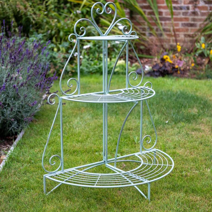 3-tier heart etager in green standing on lawn with lavender border in background.