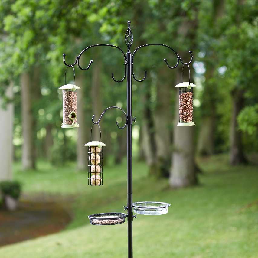 Chapelwood original dining station in black with seed, peanut and fat ball feeders hanging and wooded lawn behind