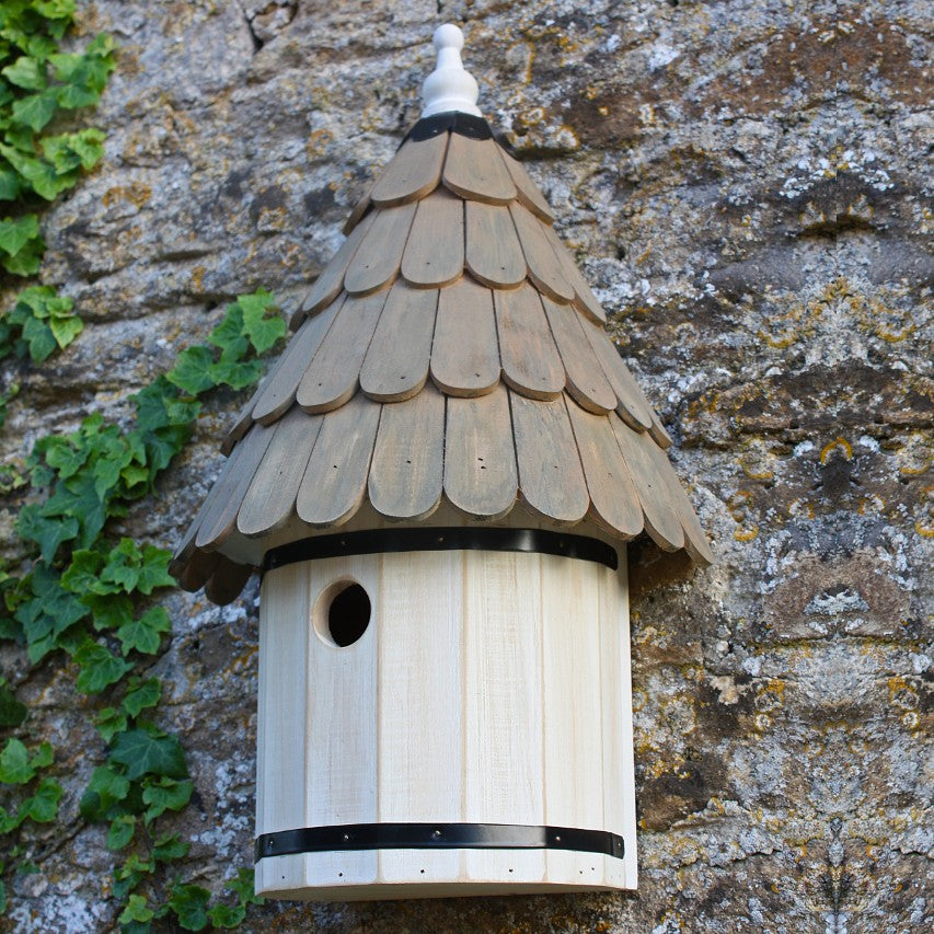 Dovecote nest box attached to stone wall with ivy growing up it